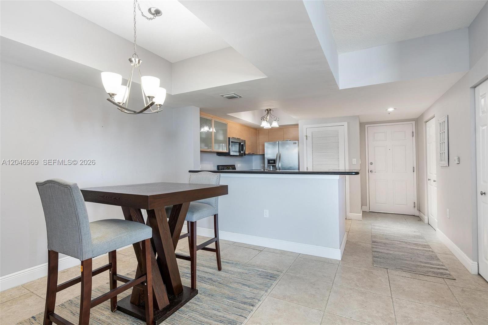 A dining area with a wooden table and chairs sits before an open kitchen — 140 S Dixie Hwy # 609, Hollywood FL 33020, HOLLYWOOD, FL