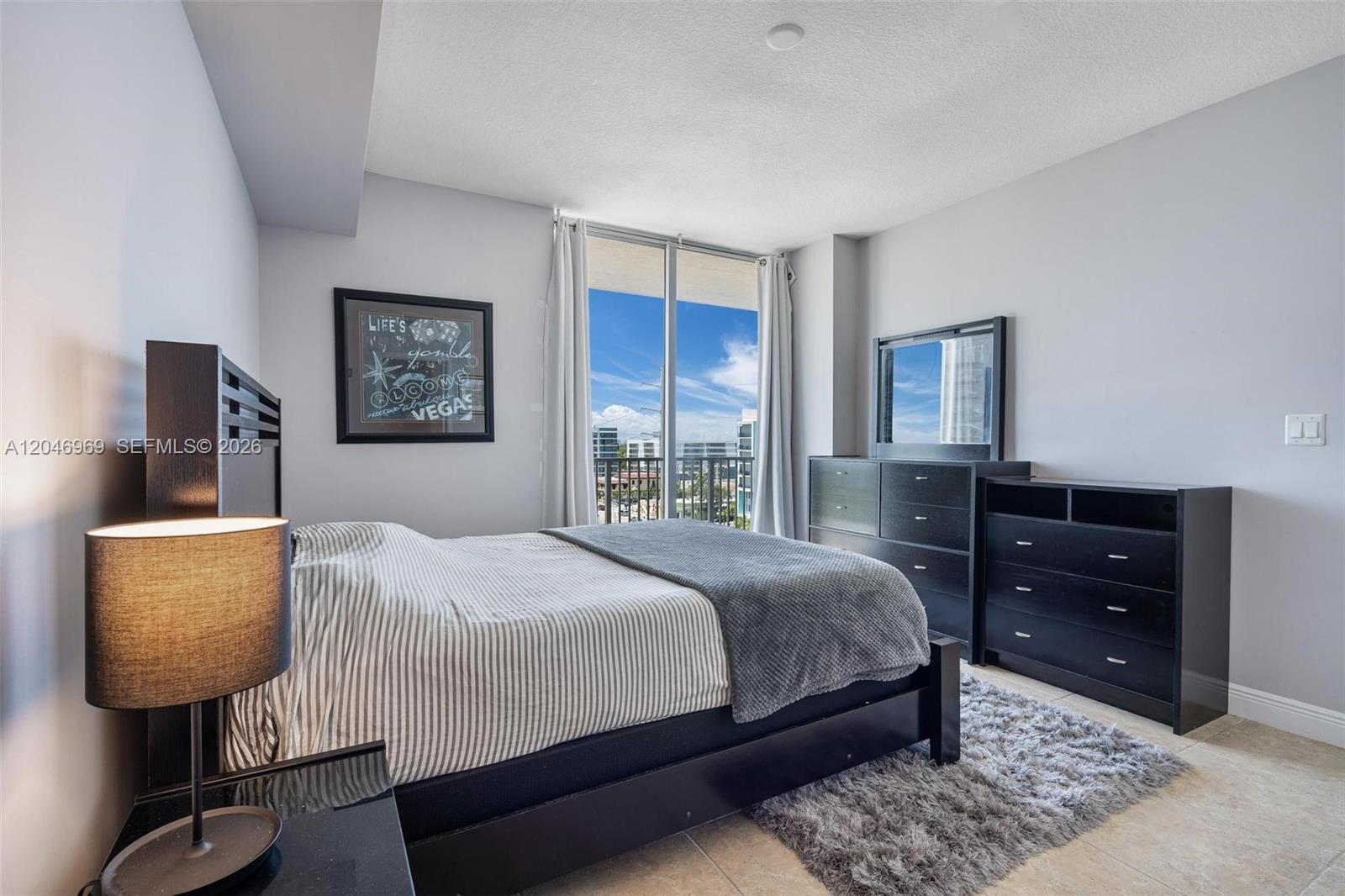 A bedroom features a dark wood bed frame, matching dressers, and a balcony with city views — 140 S Dixie Hwy # 609, Hollywood FL 33020, HOLLYWOOD, FL