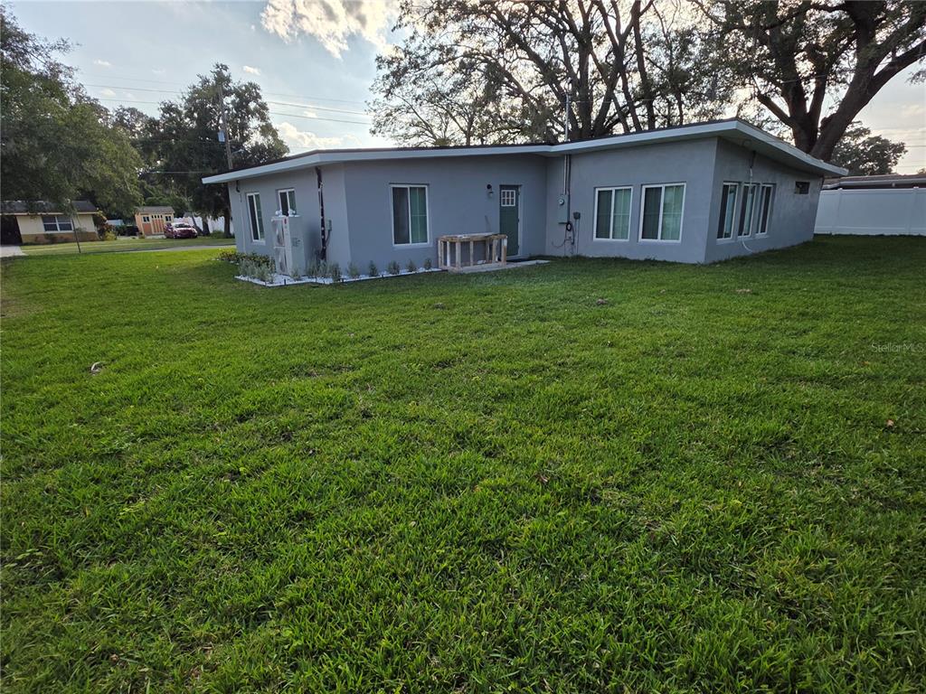 A gray, single-story house with a flat roof sits on a large, grassy lawn — 1911 W AMELIA STREET, ORLANDO, FL