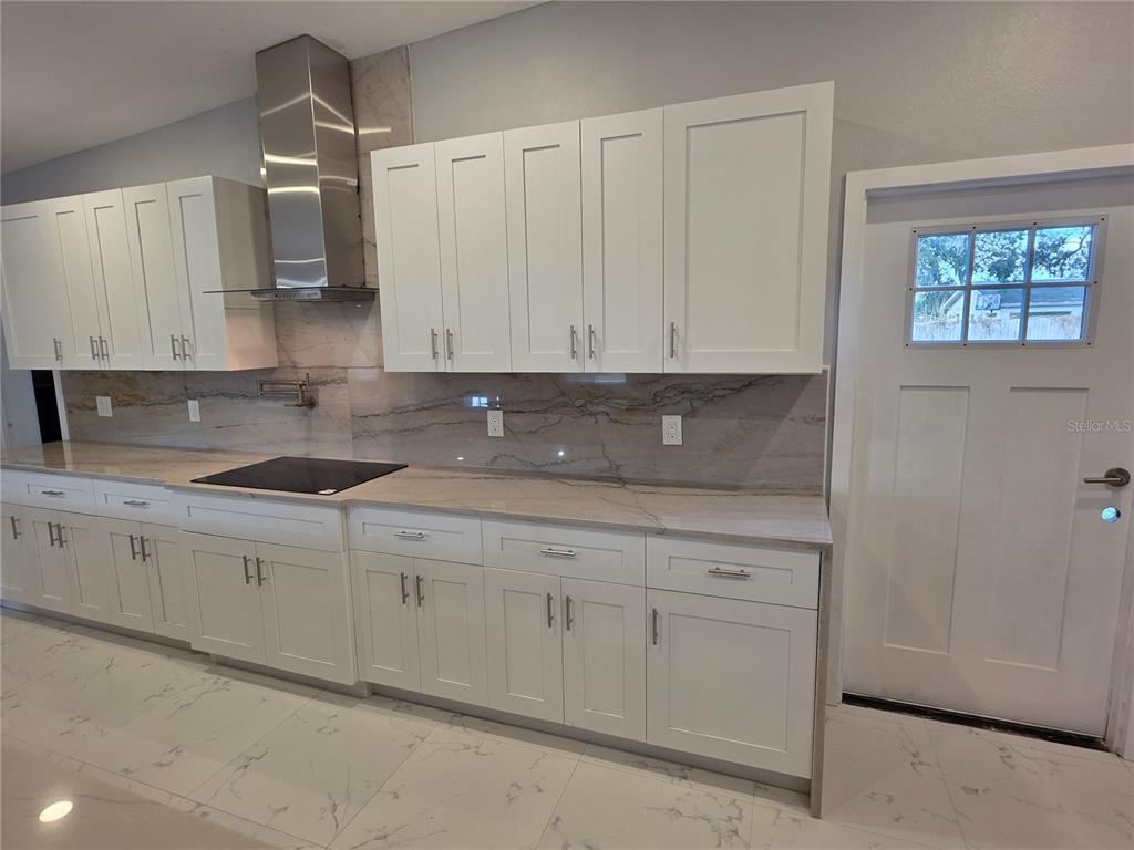A kitchen features white shaker cabinets, a stainless steel range hood, and marble-patterned countertops — 1911 W AMELIA STREET, ORLANDO, FL