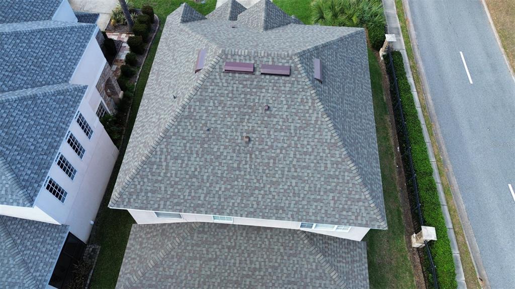 An aerial view shows the shingled roof of a house next to a paved road — 2834 EAGLE EYE COURT, KISSIMMEE, FL