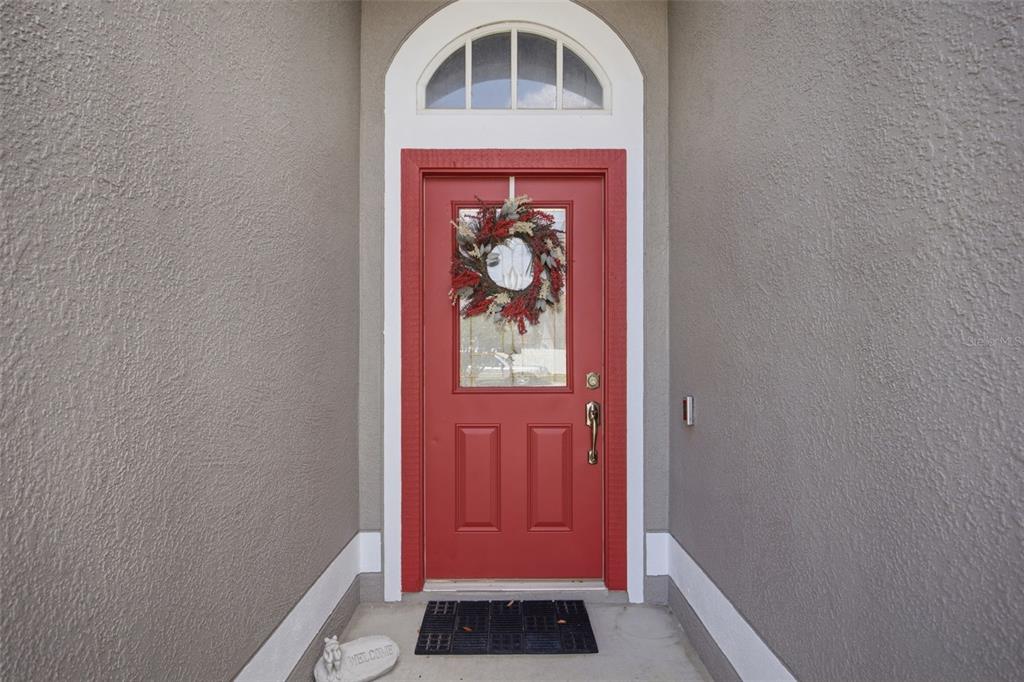 A red front door with a glass insert and wreath sits within a recessed entryway — 860 ROCKY MOUNTAIN COURT, VALRICO, FL