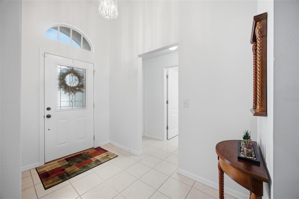 A bright entryway features white walls, tiled flooring, a front door with glass, and a console table — 860 ROCKY MOUNTAIN COURT, VALRICO, FL