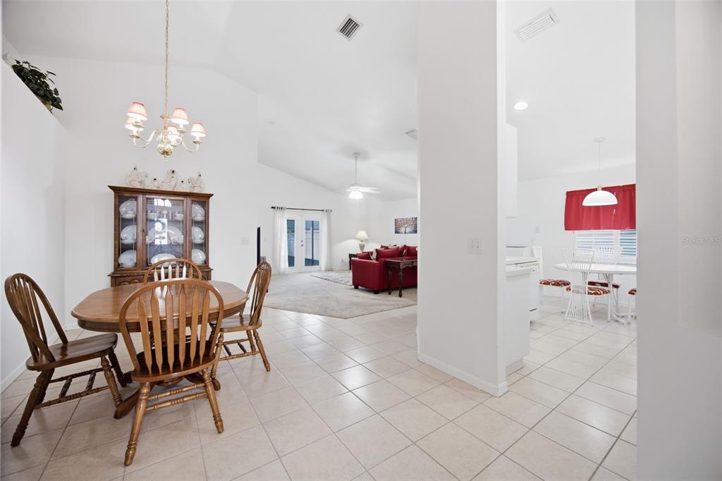 A dining area with a wooden table and chairs opens into a living room beyond — 860 ROCKY MOUNTAIN COURT, VALRICO, FL
