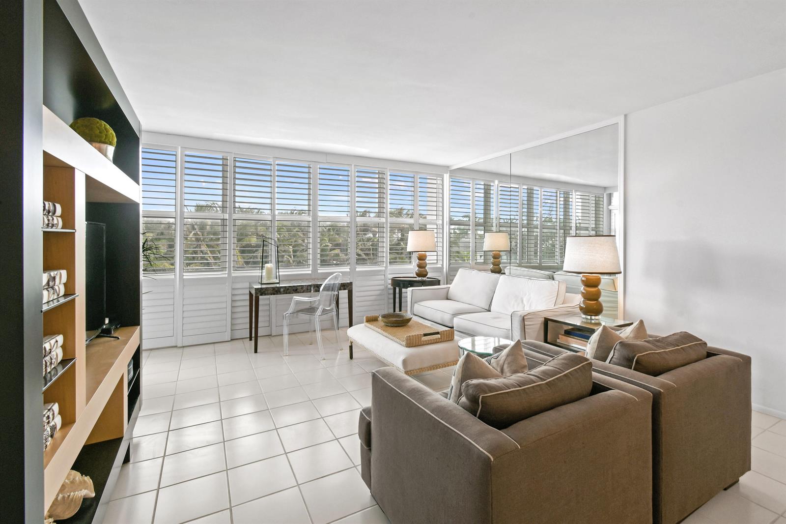 A living room features white tile floors, a large mirror, and floor-to-ceiling louvered windows — 2295 S Ocean Boulevard # 505, Palm Beach FL 33480, PALM BEACH, FL