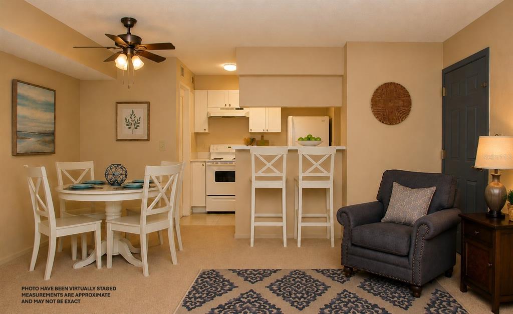 This virtually staged dining area features a white table, chairs, and an adjacent kitchen — 351 LONE HILL DRIVE UNIT 306, ALTAMONTE SPRINGS, FL