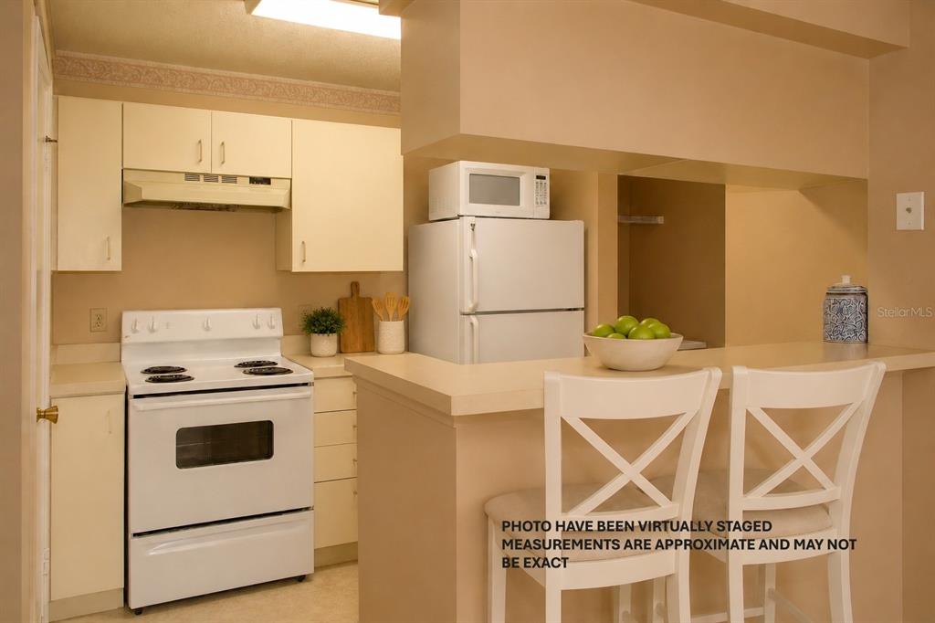 A kitchen with white appliances, beige cabinets, and a breakfast bar with two chairs — 351 LONE HILL DRIVE UNIT 306, ALTAMONTE SPRINGS, FL