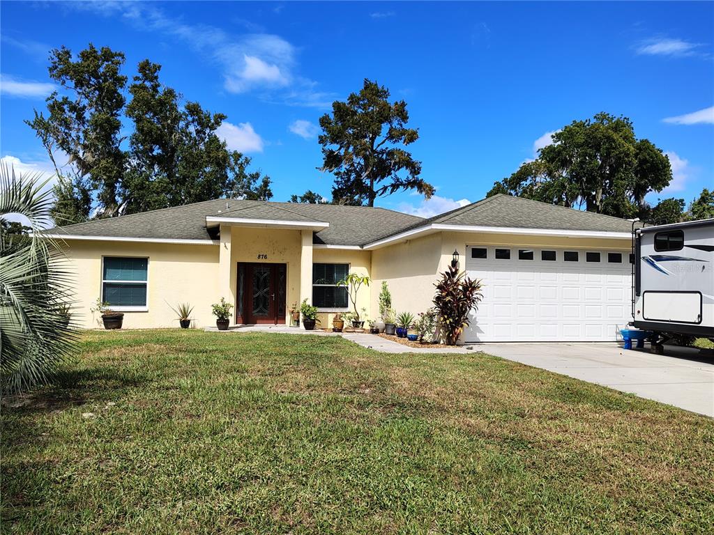 A single-story house with a light-colored exterior, a two-car garage, and a front lawn — 876 CR 467, LAKE PANASOFFKEE, FL