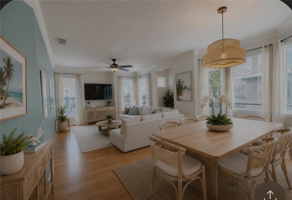 An open-concept living and dining area features light wood floors, white furniture, and coastal decor — 18058 VILLA CREEK DRIVE UNIT 18058, TAMPA, FL