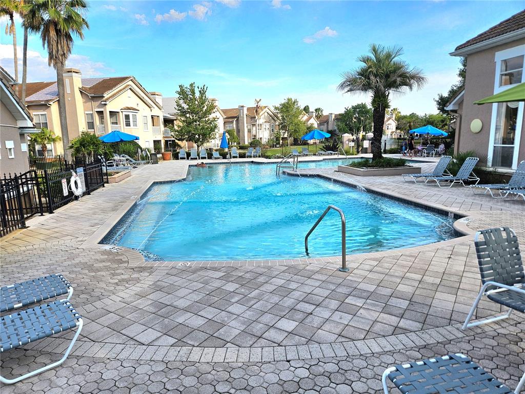 An outdoor swimming pool surrounded by a paved deck, lounge chairs, and apartment buildings — 18058 VILLA CREEK DRIVE UNIT 18058, TAMPA, FL