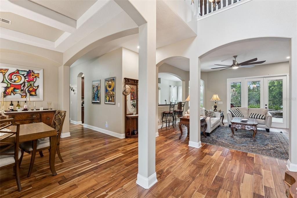 An open-concept living and dining area features hardwood floors, arched entryways, and high ceilings — 216 JUNIPER RIDGE COURT, SANFORD, FL