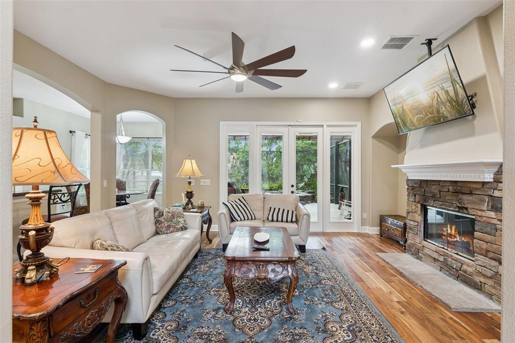 A living room features a stone fireplace, a ceiling fan, and a blue area rug — 216 JUNIPER RIDGE COURT, SANFORD, FL