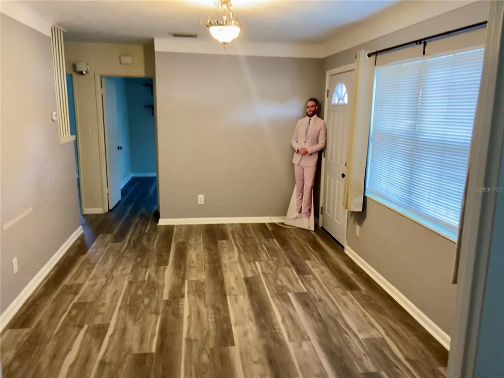 An empty room features wood-look flooring, gray walls, a ceiling light, and a cardboard cutout — 1851 50TH AVENUE N, ST PETERSBURG, FL