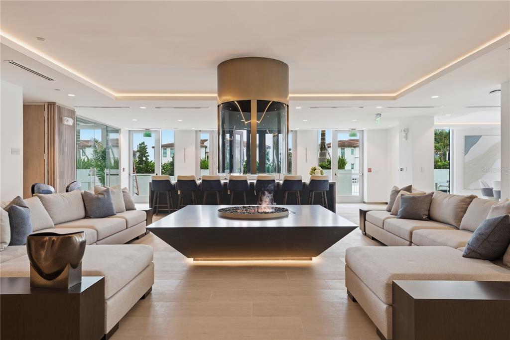 A modern lounge features a central fireplace, plush sectional sofas, and a bar area — 5713 BOWEN DANIEL DR. UNIT 1603, TAMPA, FL