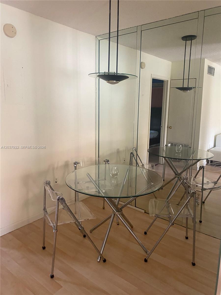 A dining area features a glass table, clear chairs, and a mirrored wall — 415 NE 2nd St # 222, Hallandale Beach FL 33009, HALLANDALE BEACH, FL