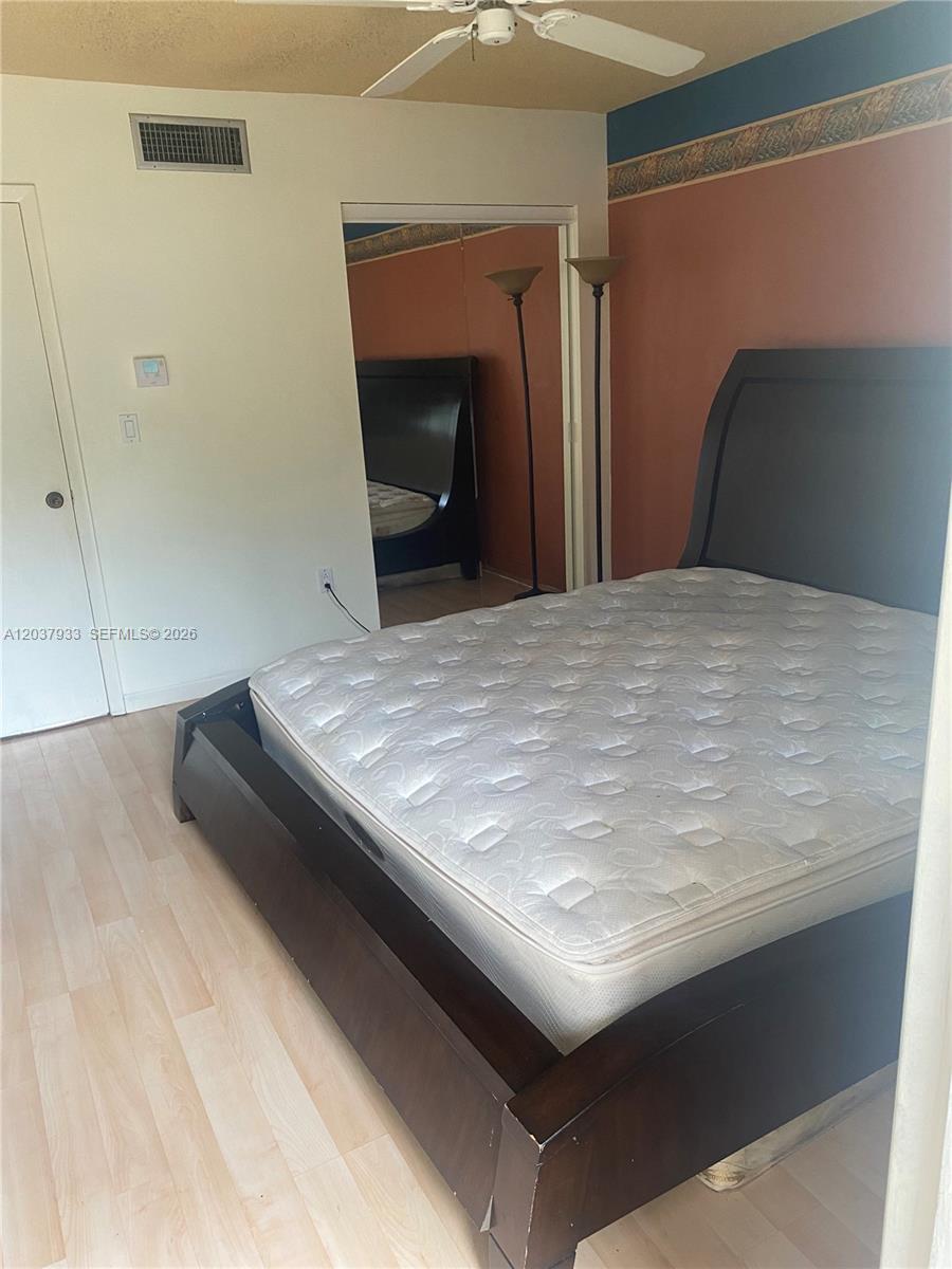 A bedroom features a dark wood bed frame, light wood flooring, and mirrored closet doors — 415 NE 2nd St # 222, Hallandale Beach FL 33009, HALLANDALE BEACH, FL