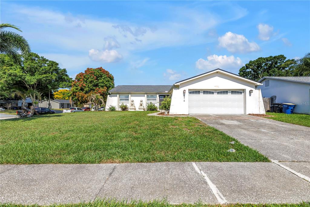A single-story house with a white exterior, a two-car garage, and a large front lawn — 3216 PINE HAVEN DRIVE, CLEARWATER, FL