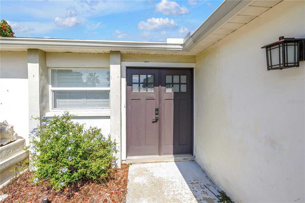 The exterior of a home features a double front door and a nearby window — 3216 PINE HAVEN DRIVE, CLEARWATER, FL
