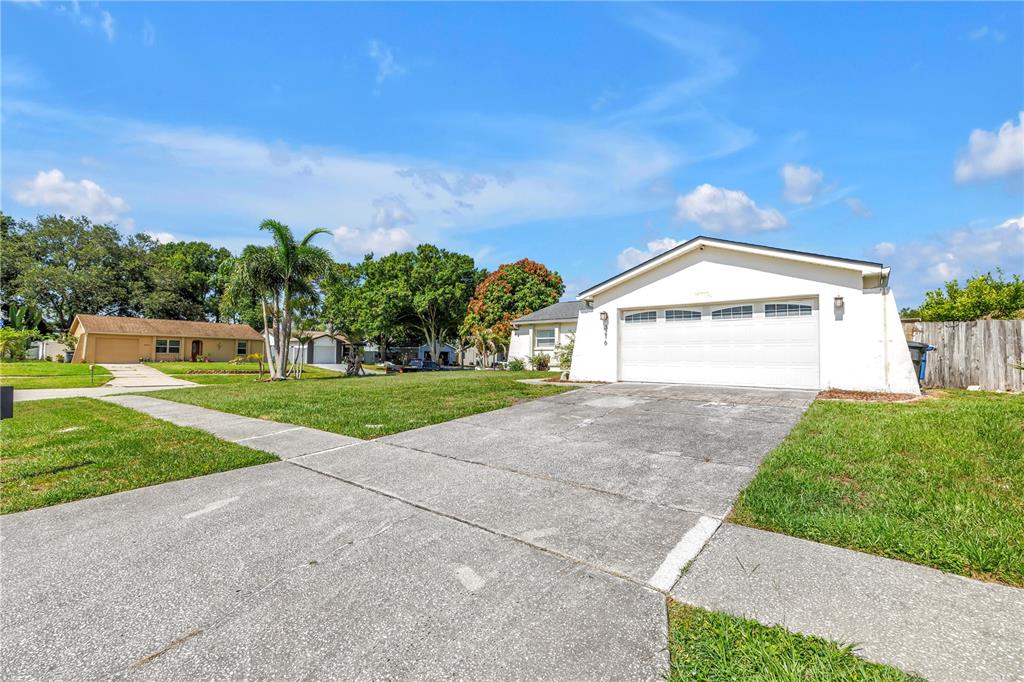 A white house with a two-car garage and a concrete driveway under a blue sky — 3216 PINE HAVEN DRIVE, CLEARWATER, FL