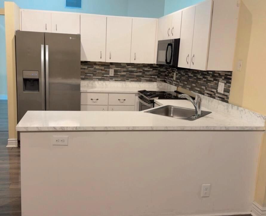 A kitchen features white cabinets, marble-look countertops, stainless steel appliances, and a mosaic tile backsplash — 7640 Forest Green Ln, Boynton Beach FL 33436, BOYNTON BEACH, FL