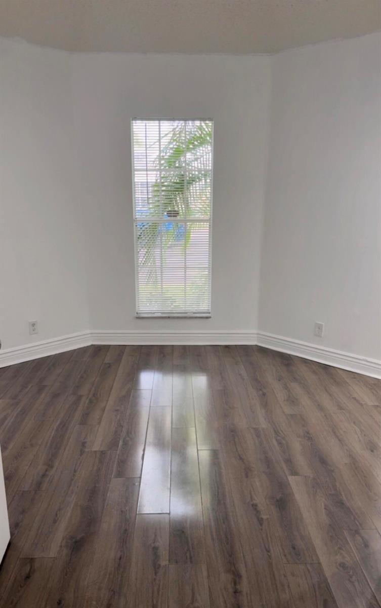 An empty room with white walls, wood-look flooring, and a single window with blinds — 7640 Forest Green Ln, Boynton Beach FL 33436, BOYNTON BEACH, FL