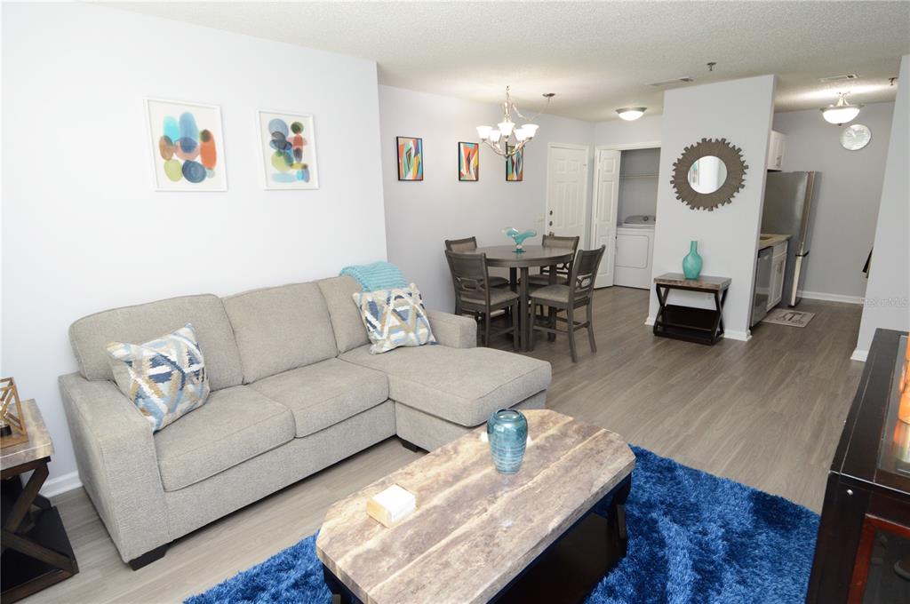 A living room with a gray sectional sofa, a coffee table, and a dining area — 11901 4TH STREET N UNIT 6106, ST PETERSBURG, FL