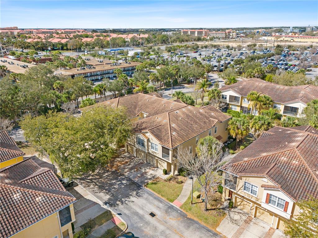 An aerial view shows multiple multi-story residential buildings with tiled roofs and attached garages — 7519 BLISS WAY UNIT 7519, KISSIMMEE, FL