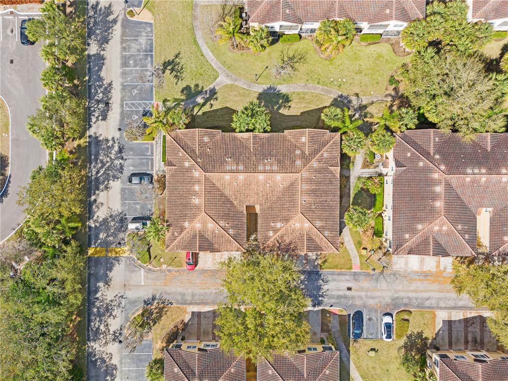 An aerial view shows several residential buildings with brown tile roofs surrounded by parking lots — 7519 BLISS WAY UNIT 7519, KISSIMMEE, FL