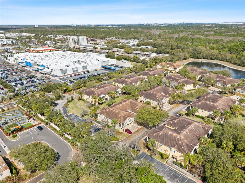 An aerial view shows multi-story residential buildings, a large commercial complex, and a small pond — 7519 BLISS WAY UNIT 7519, KISSIMMEE, FL