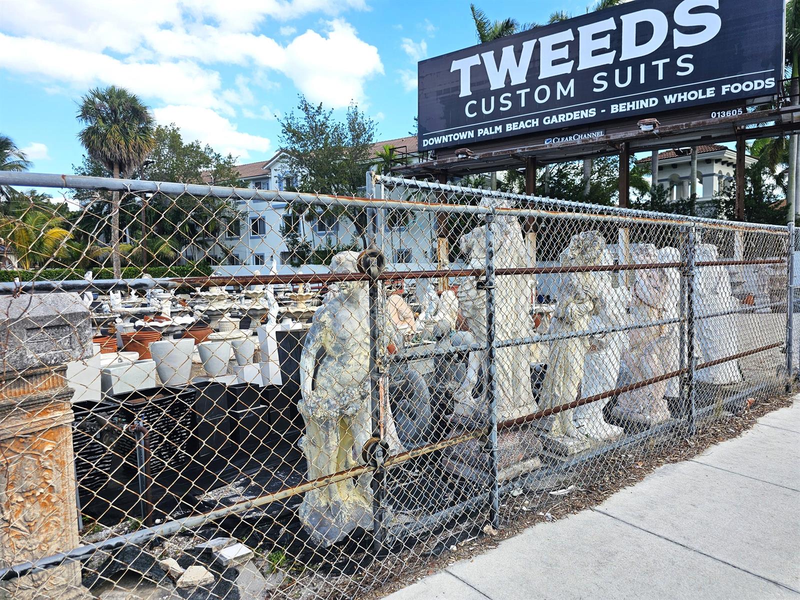 A chain-link fence encloses a collection of stone statues and planters beneath a billboard — 3675 N Federal Highway, Boynton Beach FL 33435, BOYNTON BEACH, FL