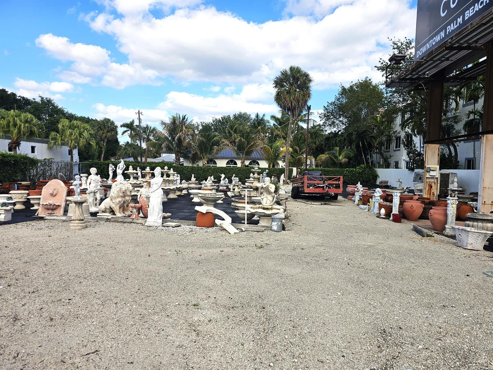 An outdoor garden supply store displays various stone statues, fountains, and planters on gravel — 3675 N Federal Highway, Boynton Beach FL 33435, BOYNTON BEACH, FL