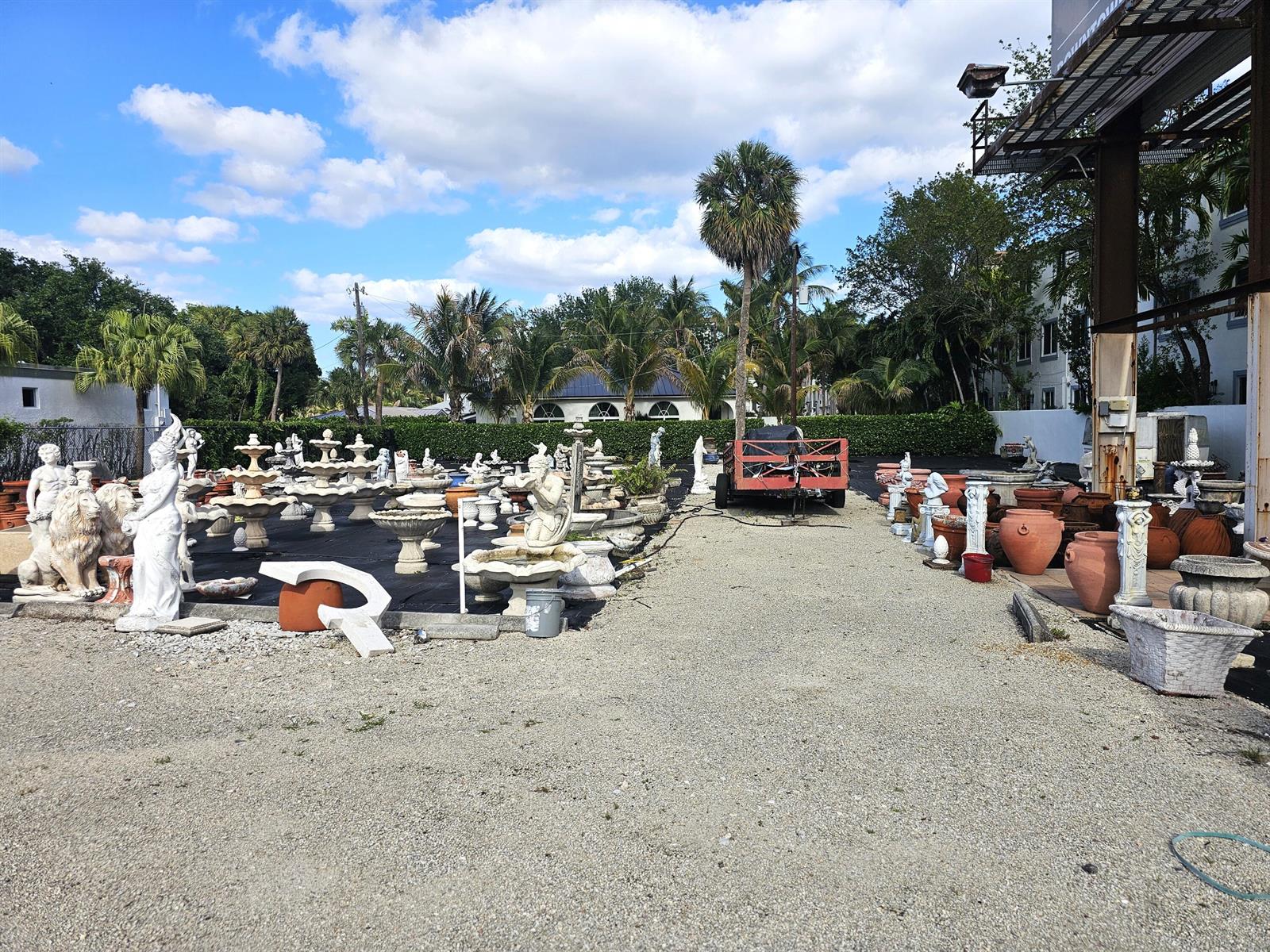 An outdoor display area features numerous stone statues, fountains, and planters on a gravel lot — 3675 N Federal Highway, Boynton Beach FL 33435, BOYNTON BEACH, FL