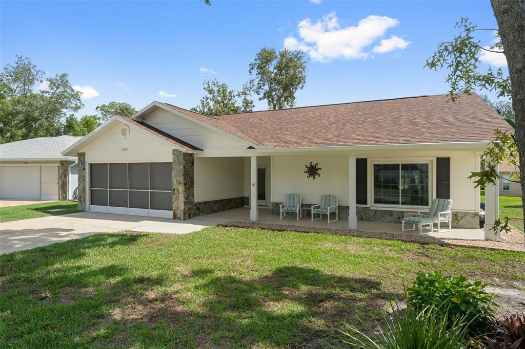 A single-story house with a screened garage, stone accents, and a covered front porch — 2224 MERION COURT, SPRING HILL, FL