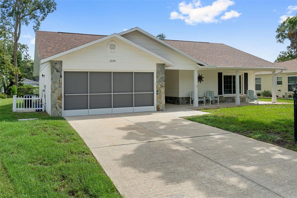 A single-story house with a screened garage, stone accents, and a covered front porch — 2224 MERION COURT, SPRING HILL, FL