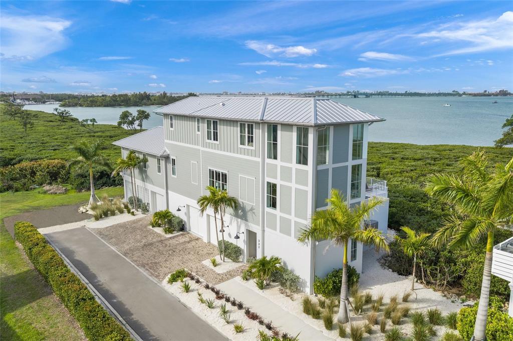 An aerial view of a multi-story coastal home with a metal roof and palm trees — 332 HARBOUR SOUND COURT, BRADENTON, FL