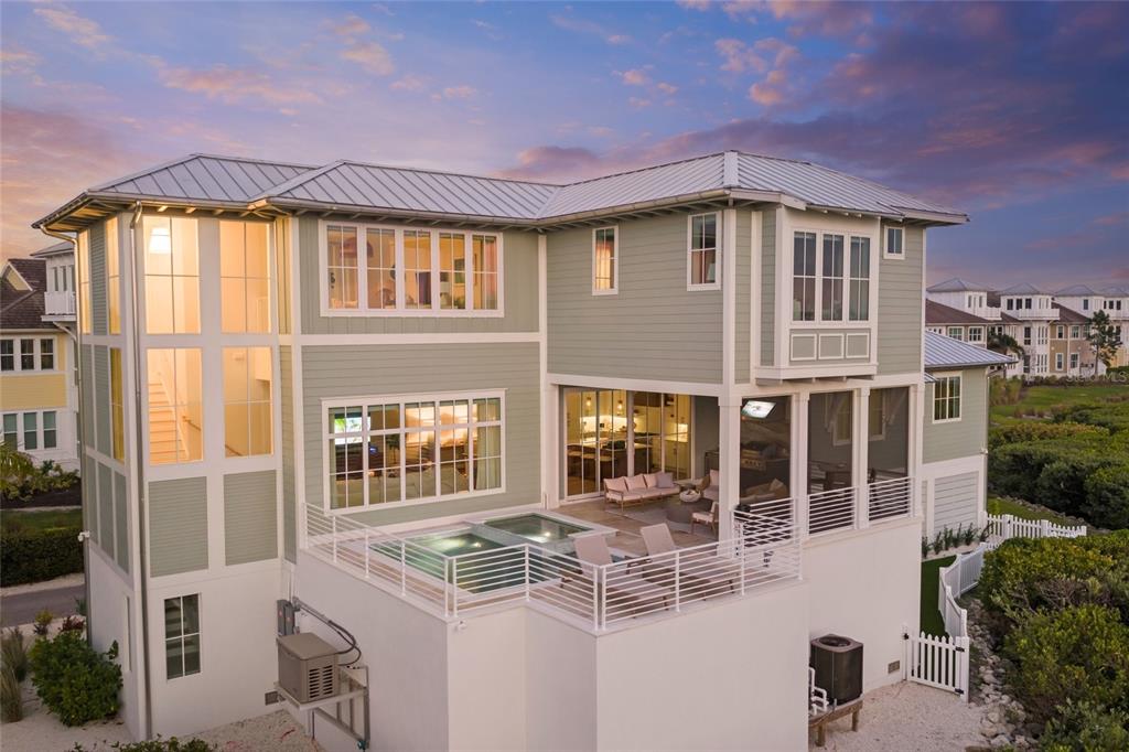 A two-story house with light green siding, a metal roof, and a raised deck with pool — 332 HARBOUR SOUND COURT, BRADENTON, FL