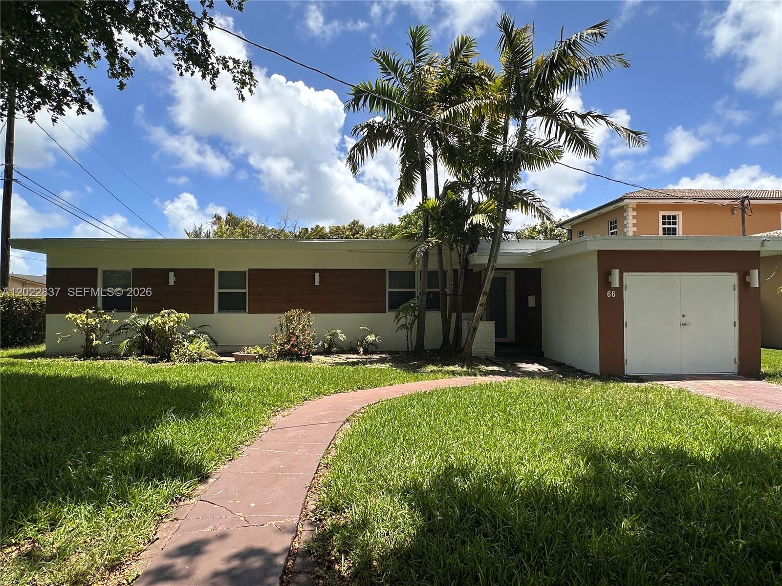A single-story house with a white and brown exterior features a palm tree and walkway — 66 NW 87th St, El Portal FL 33150, EL PORTAL, FL