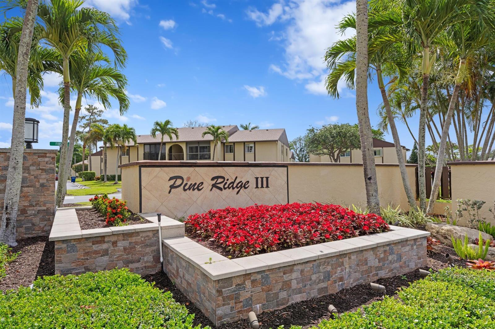 The exterior entrance sign for Pine Ridge III features stone masonry and red flower beds — 337 Pine Ridge Circle # 2, FL 33463, FL