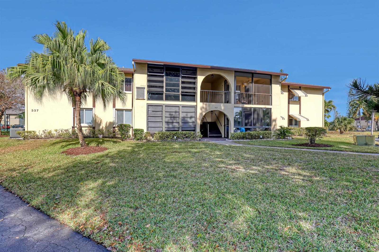 A two-story apartment building with a palm tree, arched entryways, and screened balconies — 337 Pine Ridge Circle # 2, FL 33463, FL