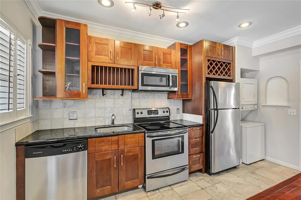 A kitchen features wood cabinets, stainless steel appliances, granite countertops, and a stacked laundry unit — 201 6TH STREET S UNIT 102, ST PETERSBURG, FL