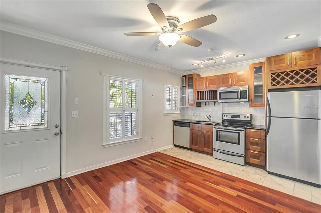 A kitchen with wood cabinets, stainless steel appliances, and hardwood flooring opens to a dining area — 201 6TH STREET S UNIT 102, ST PETERSBURG, FL