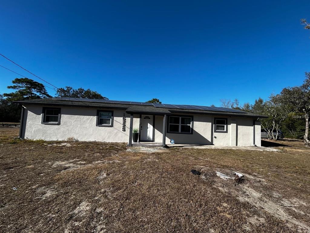 A single-story house with a stucco exterior and solar panels on the roof — 16225 WHIPPOORWILL LANE, SPRING HILL, FL