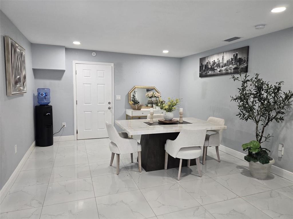 A dining room features a marble-topped table, white chairs, light tile flooring, and a door — 16225 WHIPPOORWILL LANE, SPRING HILL, FL