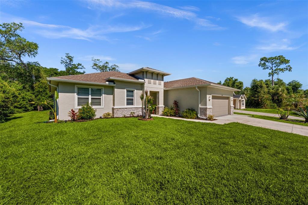 A single-story house with a tan stucco exterior, stone accents, and a two-car garage — 4831 OCALA TERRACE, NORTH PORT, FL