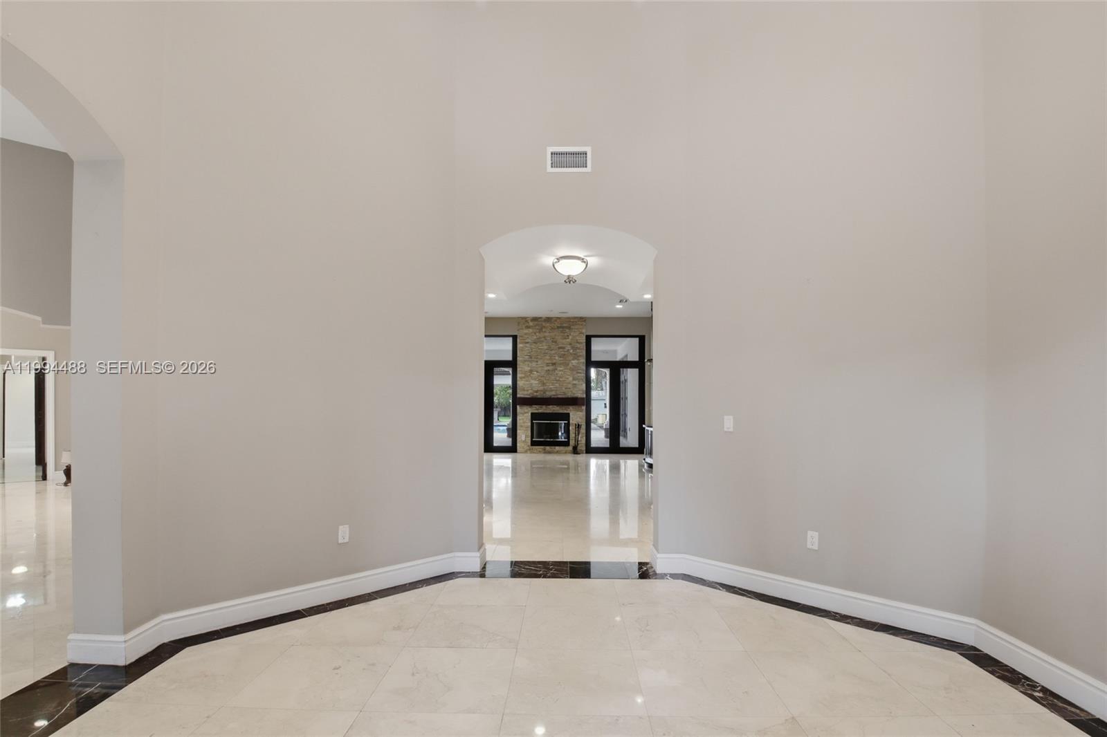 A light-colored foyer with marble flooring leads through an arched doorway to a living area — 6200 SW 97th Ave, Miami FL 33173, MIAMI, FL