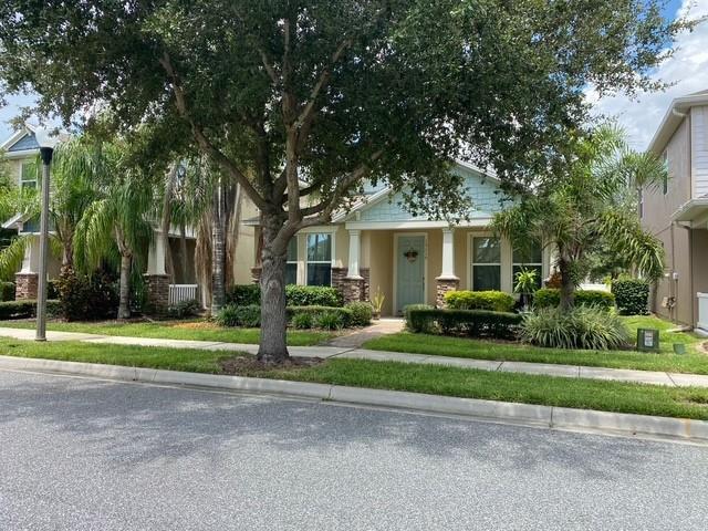 A single-story house with a light blue facade, stone accents, and a large front tree — 15115 Pigeon Plum Lane, FL 34787, FL