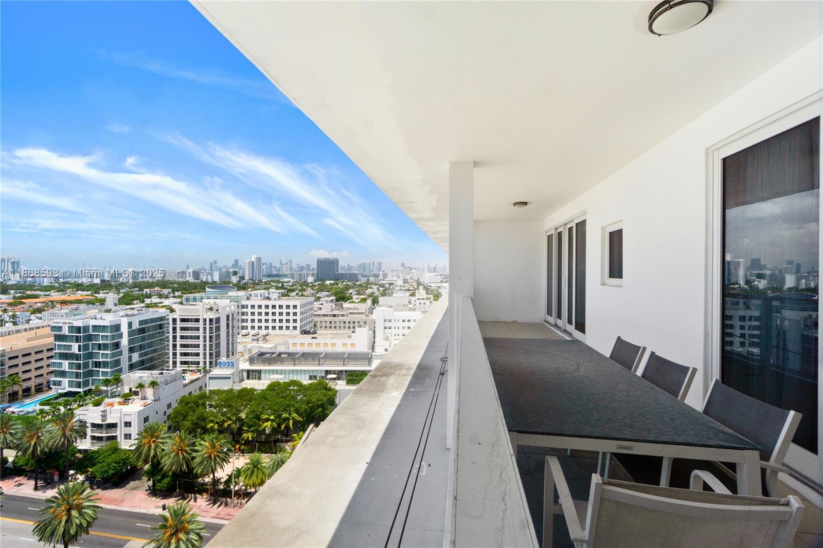 A high-rise balcony features a dining set overlooking a city skyline and palm trees — 100 Lincoln Rd, Miami Beach FL 33139, MIAMI BEACH, FL