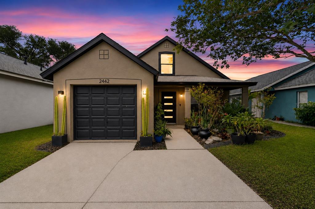 A single-story house with a garage, a front porch, and a concrete driveway at dusk — 2442 SAGEMONT DRIVE, BRANDON, FL