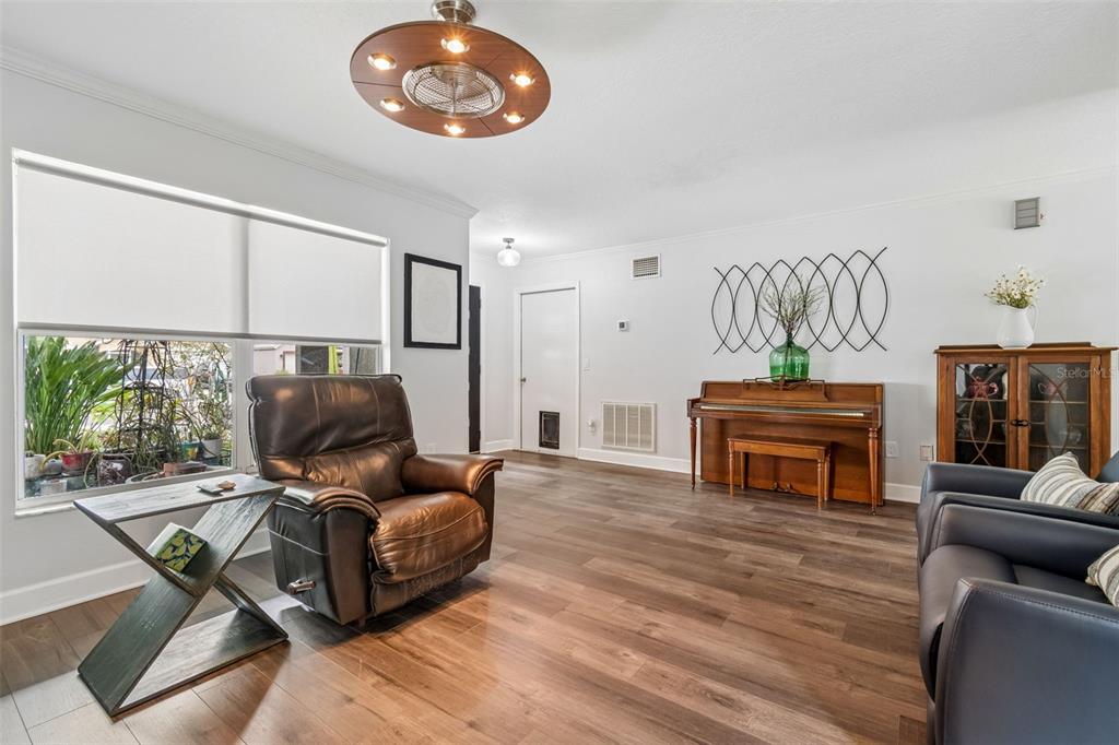 A living room features wood-look flooring, a brown leather recliner, and an upright piano — 2442 SAGEMONT DRIVE, BRANDON, FL