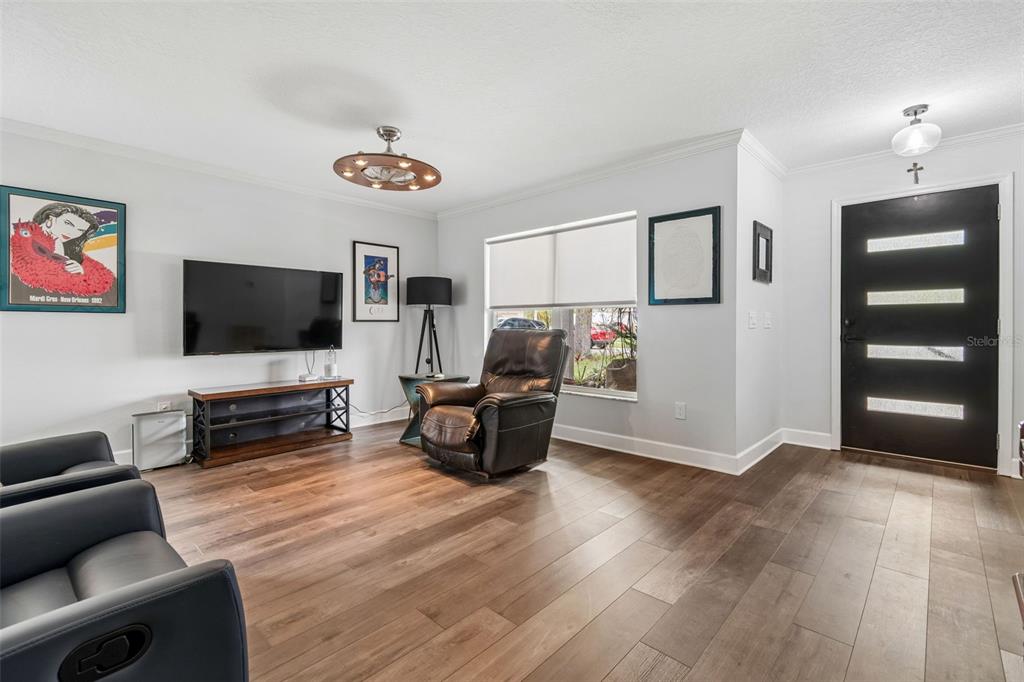 A living room features a dark leather recliner, a wall-mounted television, and wood-look flooring — 2442 SAGEMONT DRIVE, BRANDON, FL
